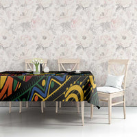 Black tablecloth with multicolor African geometric pattern on dining table with chairs.
