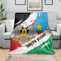 Flag-themed blanket on sofa with eagle crest, blue star, and SOUTH SUDAN text