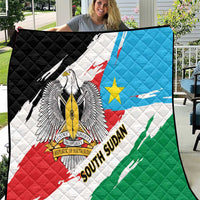 South Sudan flag quilt held open outdoors, quilted surface with eagle crest and flag design.