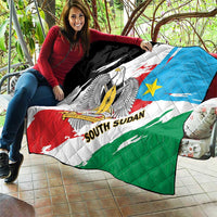 South Sudan flag quilt laid on a patio, eagle emblem centered with diagonal flag bands.