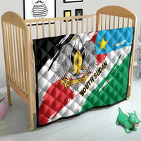 South Sudan flag quilt covering a toddler bed, showing eagle emblem and tricolor stripes.