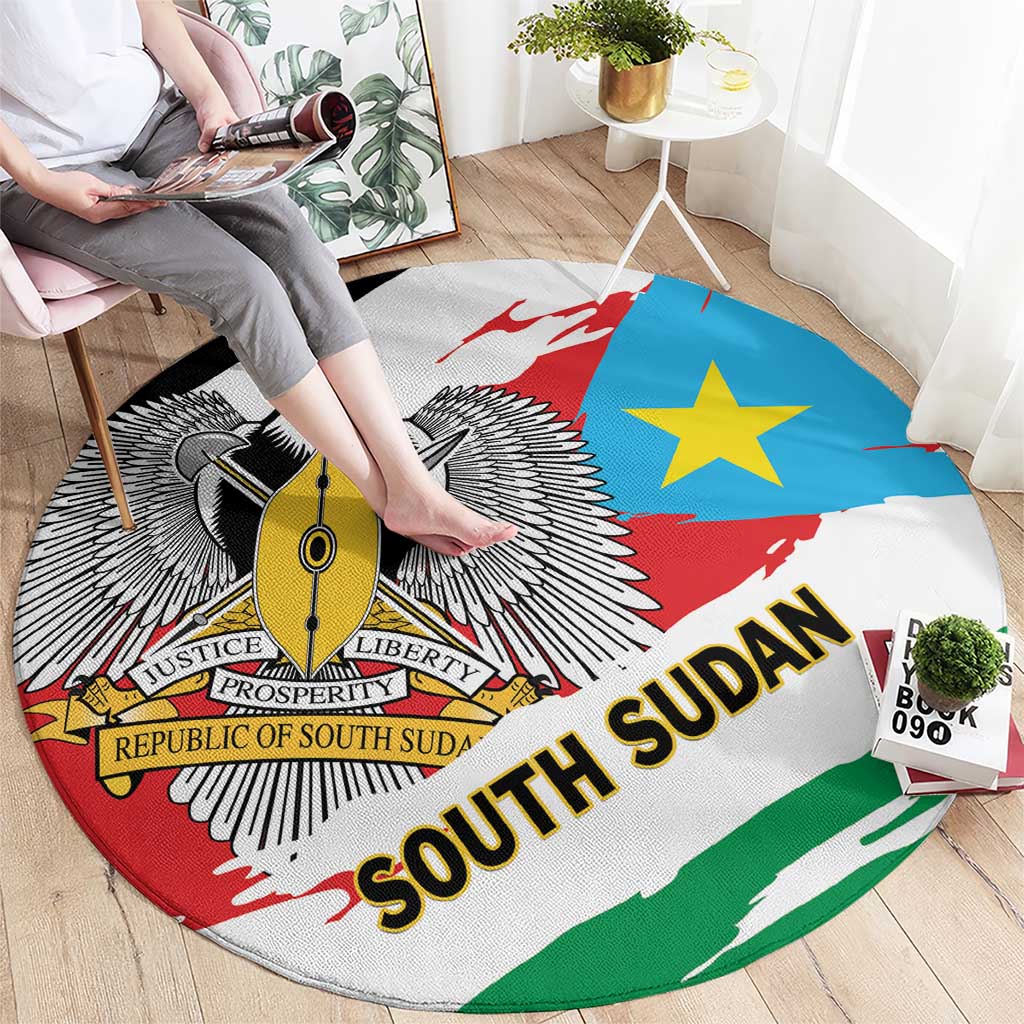 Round area rug on floor with South Sudan flag design, winged emblem, blue star, “SOUTH SUDAN”