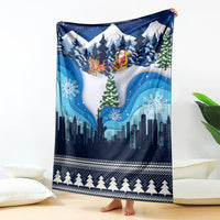 Blue Christmas blanket with snow city skyline, pine trees, and reindeer sleigh art.