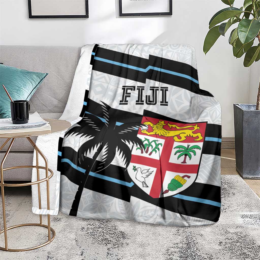 Fiji rugby blanket on floor with blue and black stripes, shield emblem, and palm prints