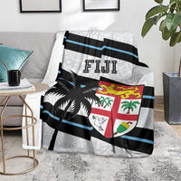Fiji rugby blanket on floor with blue and black stripes, shield emblem, and palm prints