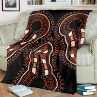Black blanket with bold dashiki motifs, draped over armchair with pillows