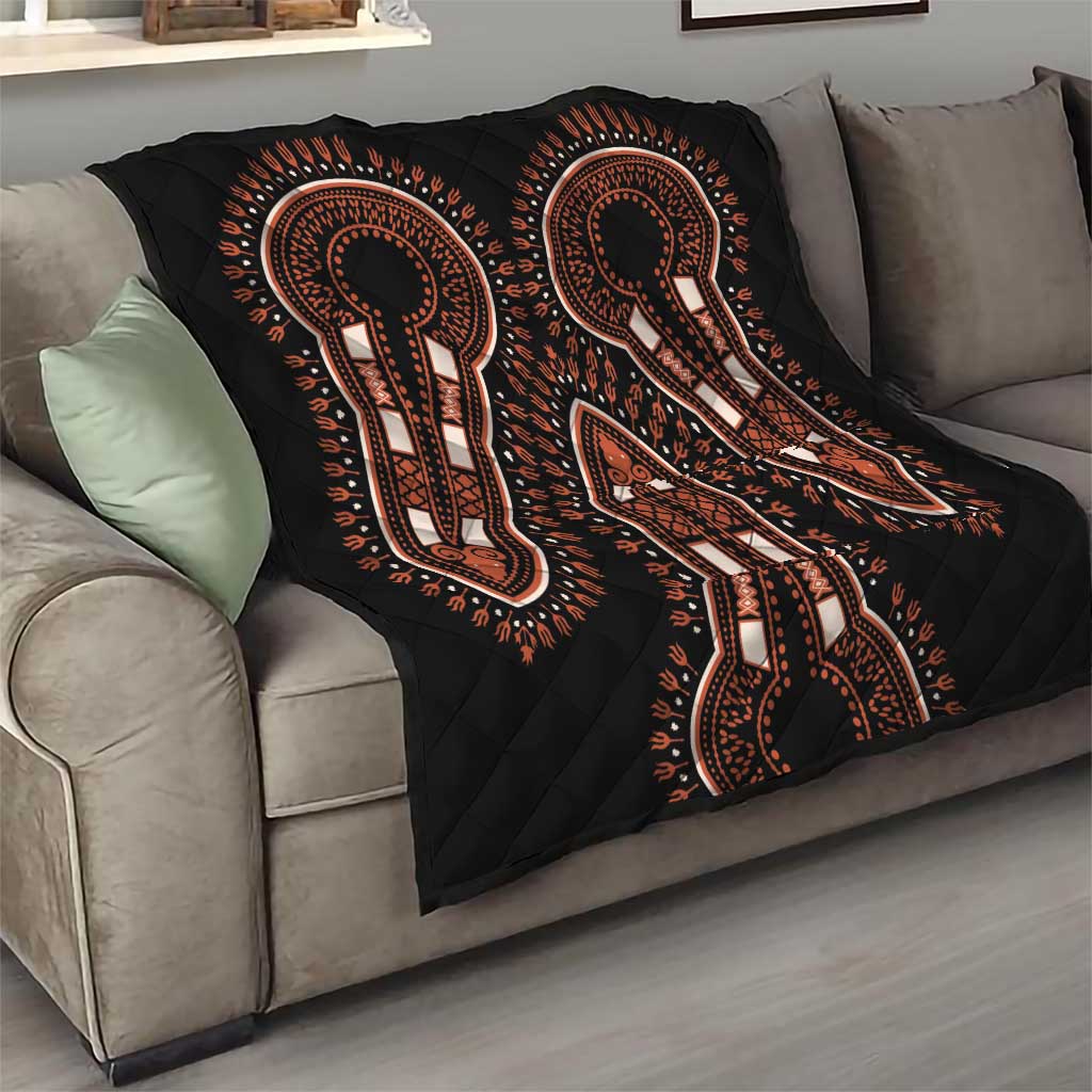 Black quilt throw with orange and white elephant silhouettes on sofa, diamond-quilted