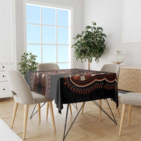 Black tablecloth with orange dashiki pattern, draped over dining table