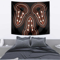 Black wall tapestry featuring orange ornamental figures with centered head-and-body motif
