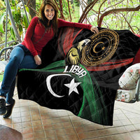 Black quilted blanket draped on seating, showing Libya crescent, star, and eagle