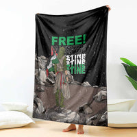 Black throw blanket with green 'FREE' and 'PALESTINE' text, displayed and spread