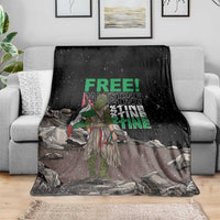 Black throw blanket with green 'FREE' and stacked 'PALESTINE' text, spread on sofa