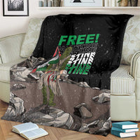 Black throw blanket with green 'FREE' and 'PALESTINE' text, draped across couch
