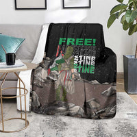 Black throw blanket with green 'FREE' and protest graphic, laid on chair