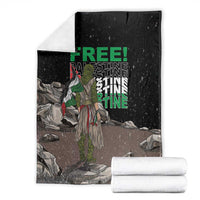 Black throw blanket with green 'FREE' and 'PALESTINE' text, with rolled white towels