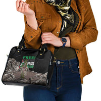 Black shoulder handbag with top handles and front graphic, held at waist