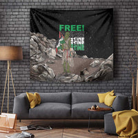 Black tapestry wall hanging with green “FREE!” text, central figure, and rock pile design