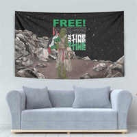 Black tapestry wall hanging showing green “FREE!” text, standing figure, and gray rock background