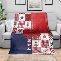 Christmas patchwork blanket on a sofa with red and navy sections, star accents, and red bow.