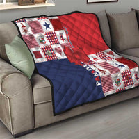 Patchwork Christmas quilt draped on sofa in red, navy and white with bow applique
