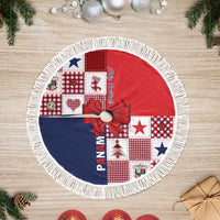 Round red and navy tree skirt with plaid patchwork, bow center, and white fringe