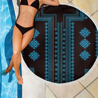 Round blue patterned beach blanket with white fringe, draped on a bather