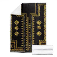 Folded dark blanket featuring gold geometric stripes and side panels
