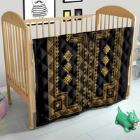 Black quilt blanket with gold vertical geometric panels and diamond motifs on a baby bed.
