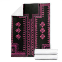 Black and pink patterned throw blanket shown folded with matching folded white items