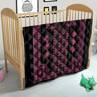 Black quilt blanket with pink geometric panels and diamond motifs in a crib.