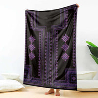 Black blanket with purple vertical border and diamond motifs, draped over the floor