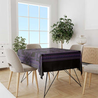 Purple and black traditional geometric tablecloth on a dining table with side chair backs.