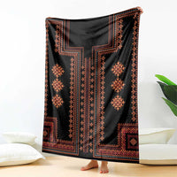 Black woven blanket with bold vertical geometric motifs and orange-red accents, draped