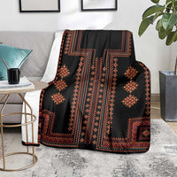 Black decorative blanket with orange-red diamond and cross patterns, draped over a gray chair