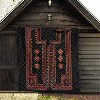 Black quilt with red geometric border and diamond motif panels displayed in a barn.
