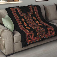 Black quilt with red geometric stripe design and diamond medallions on a sofa.