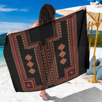 Black sarong close-up with red geometric cross and diamond motifs, draped wrap fabric