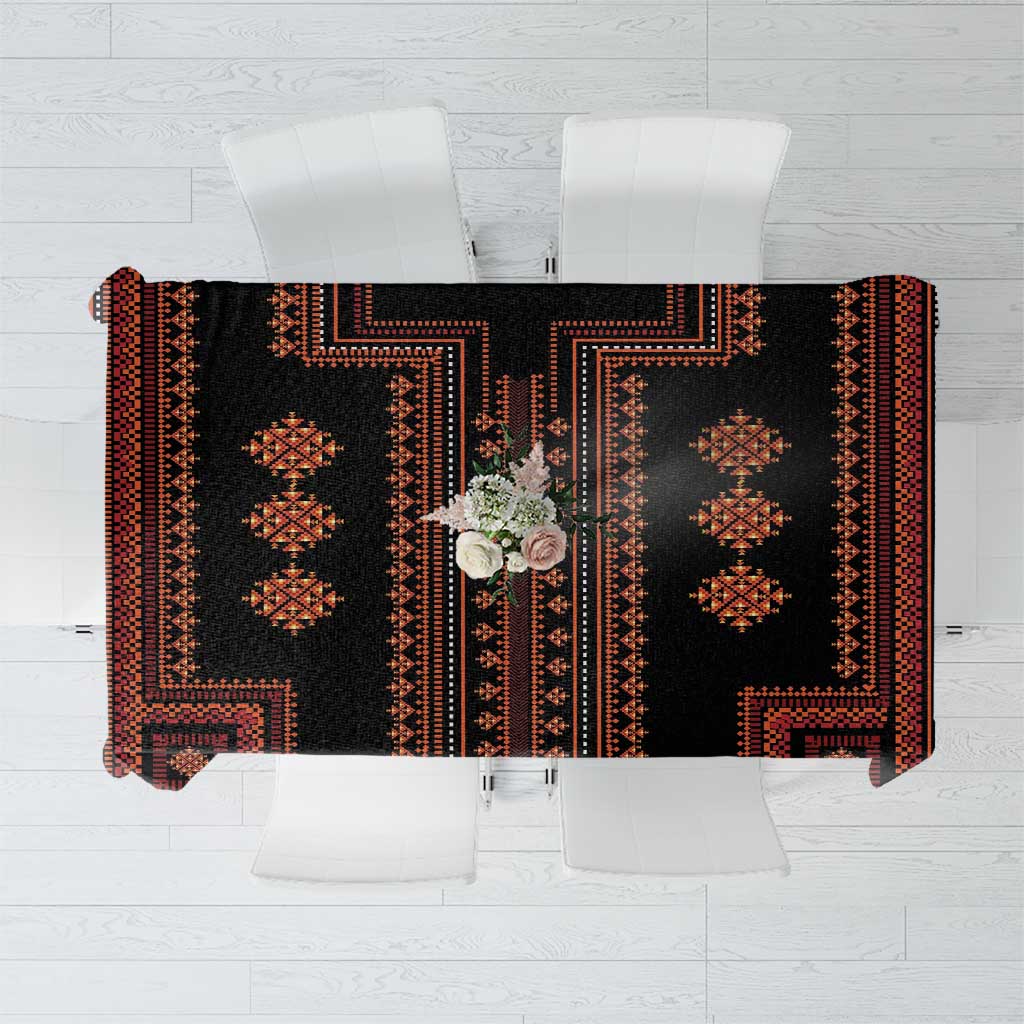 Traditional tablecloth laid flat showing black fabric with red-orange panel motifs