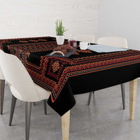 Close dining view of black tablecloth with red-orange geometric trim and motifs
