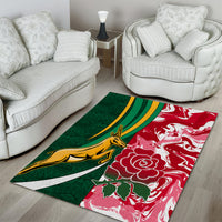 Rectangular area rug with green background, red floral print, and gold emblem