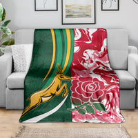 Rugby blanket draped on a couch: green left, red right, yellow animal and white flowers