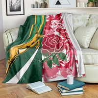 Rugby blanket with green and red print, yellow animal figure, and white floral accents