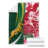 Folded rugby blanket showing green and red panels with yellow animal and white flower motifs