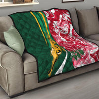 Green and red quilt draped on a sofa with gold springbok, white stripes, and flowers