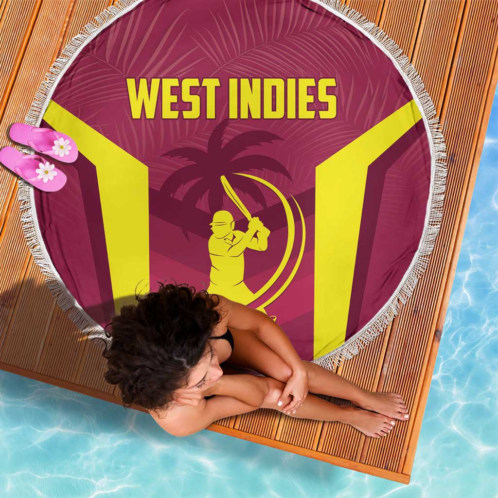 Maroon round beach blanket with white fringe, West Indies logo and text