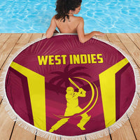 Maroon round beach blanket with white fringe, West Indies emblem and text