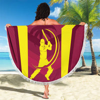 Maroon round beach blanket with white fringe, West Indies logo, held open