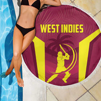 Maroon round beach blanket with white fringe, West Indies logo and text