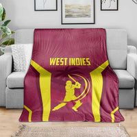Maroon cricket throw blanket with WEST INDIES lettering and batter icon, spread on sofa