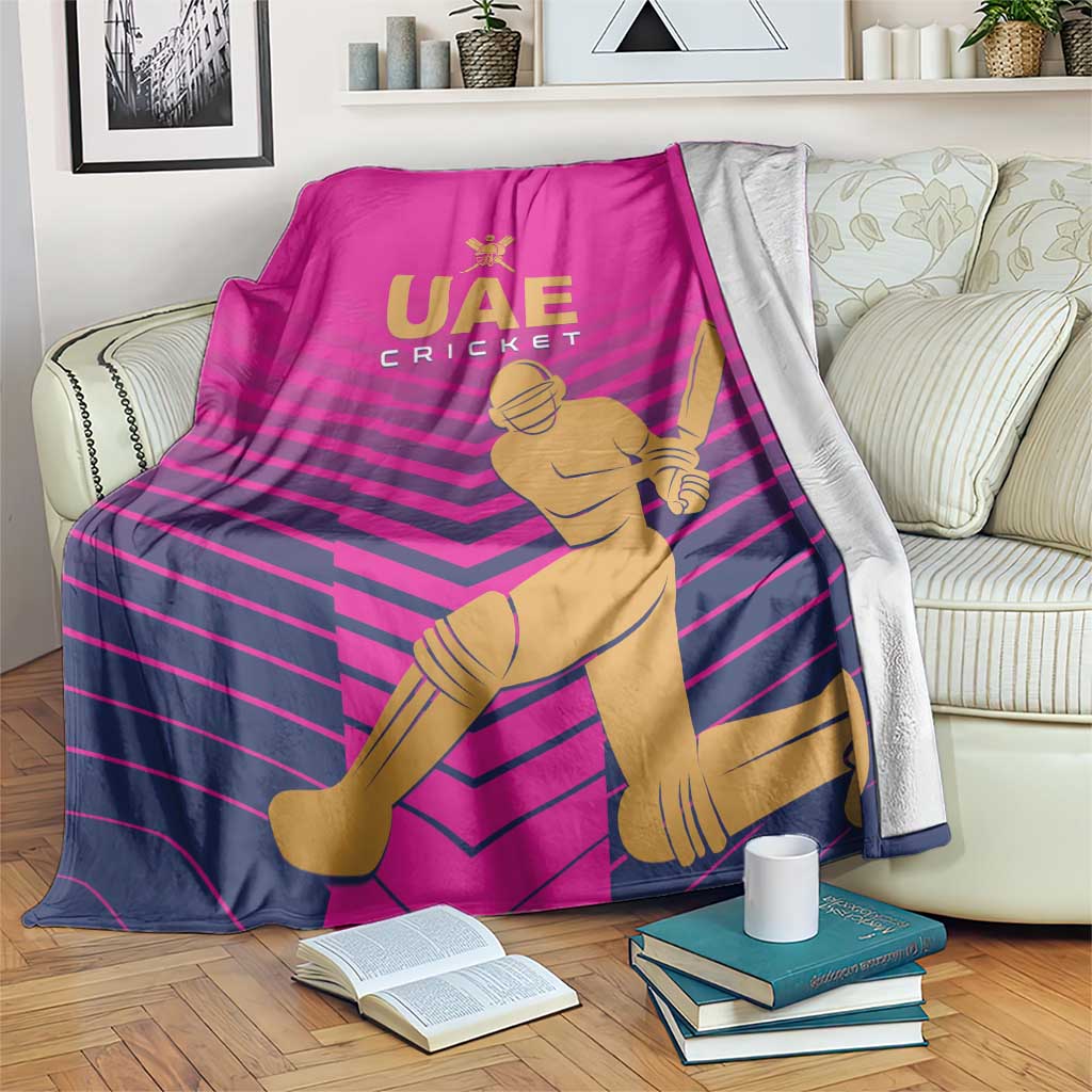 Pink UAE Cricket blanket with gold player graphic and dark striped pattern, folded over couch